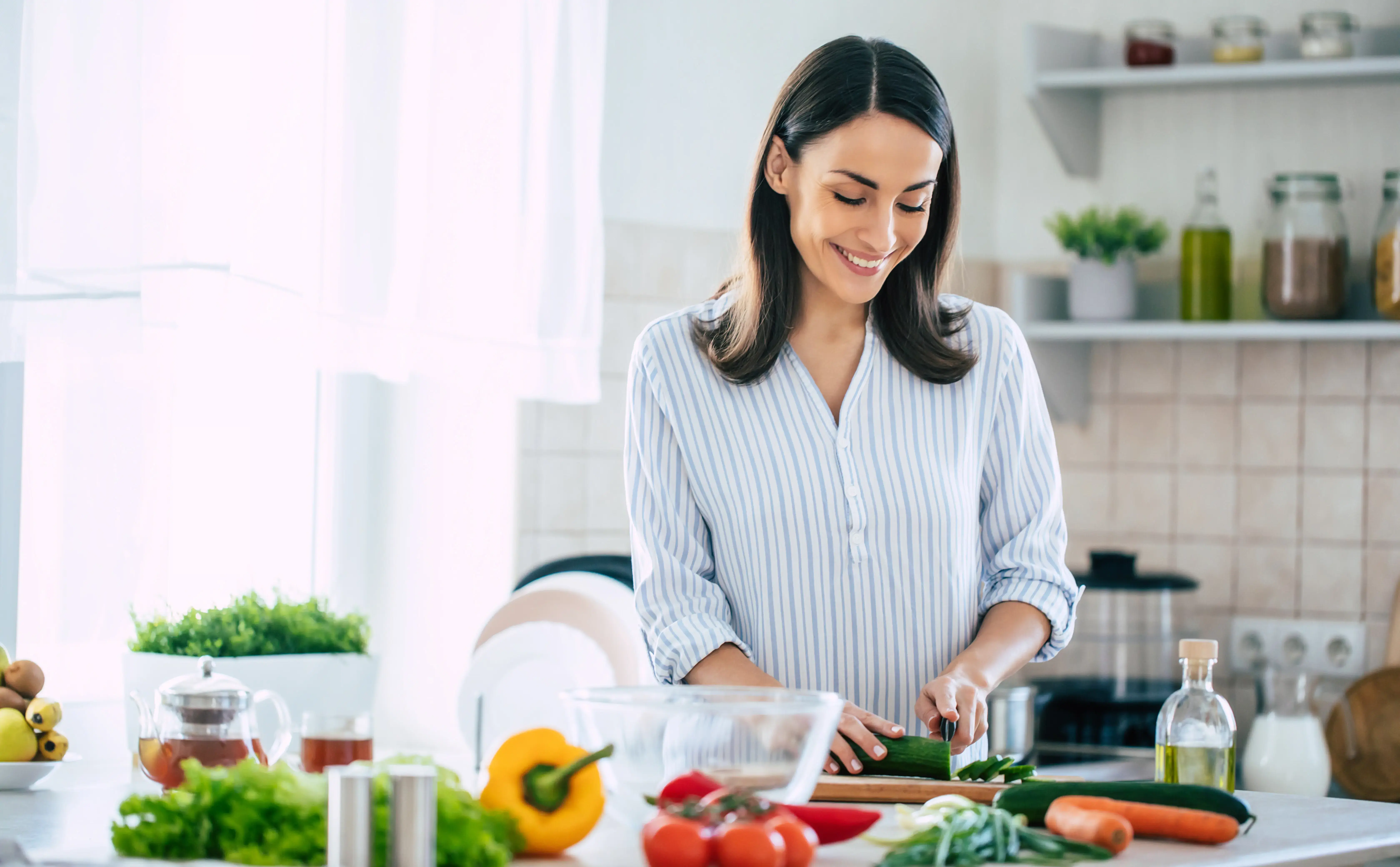 Einfach Abnehmen - Happy brunette woman in good mood preparing a fresh vegan salad for a healthy life in the kitchen of her home