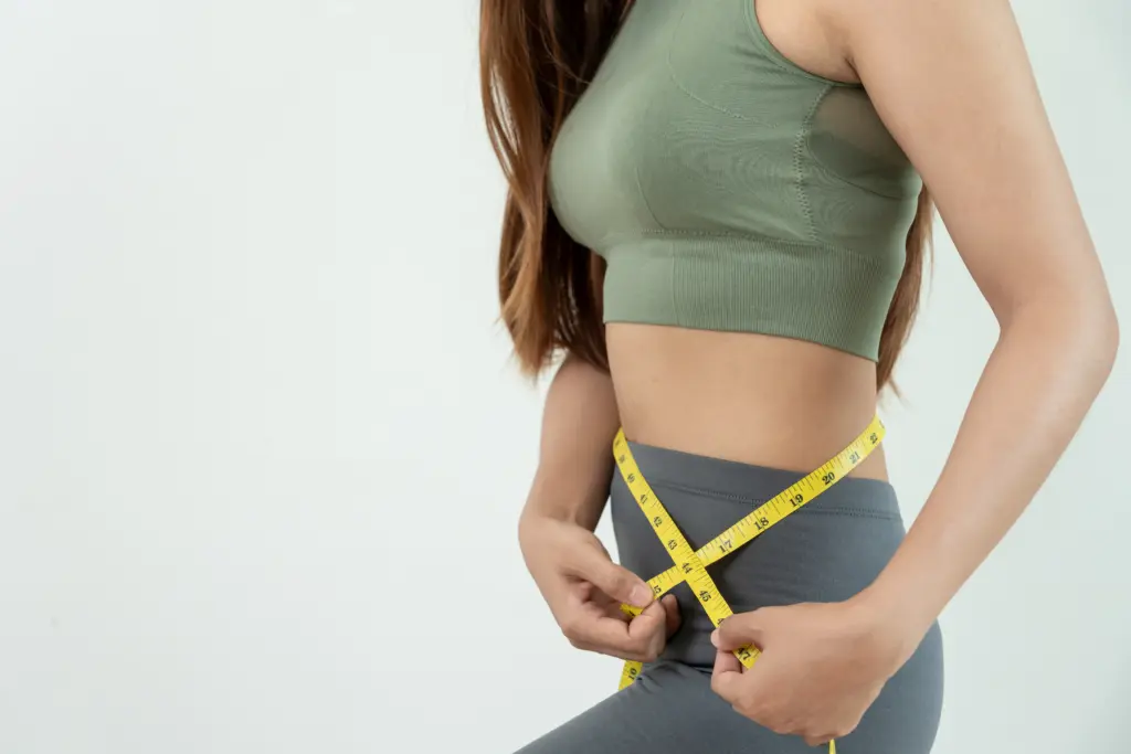Diet and dieting. Beauty slim female body use tape measure. Woman in exercise clothes achieves weight loss goal for healthy life, crazy about thinness, thin waist, nutritionist.