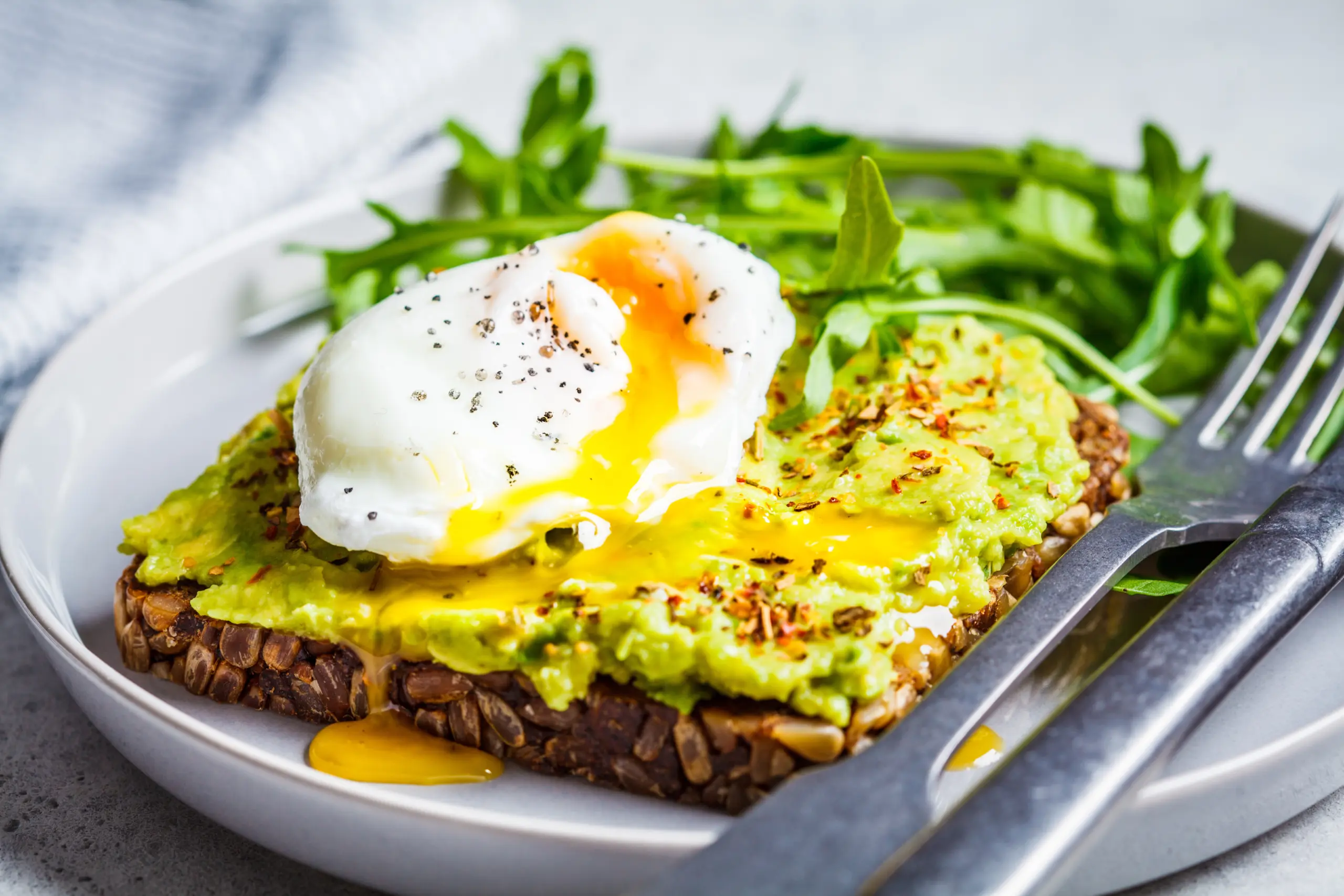 vocado toast with poached egg on a gray plate. Vegetarian healthy food concept.